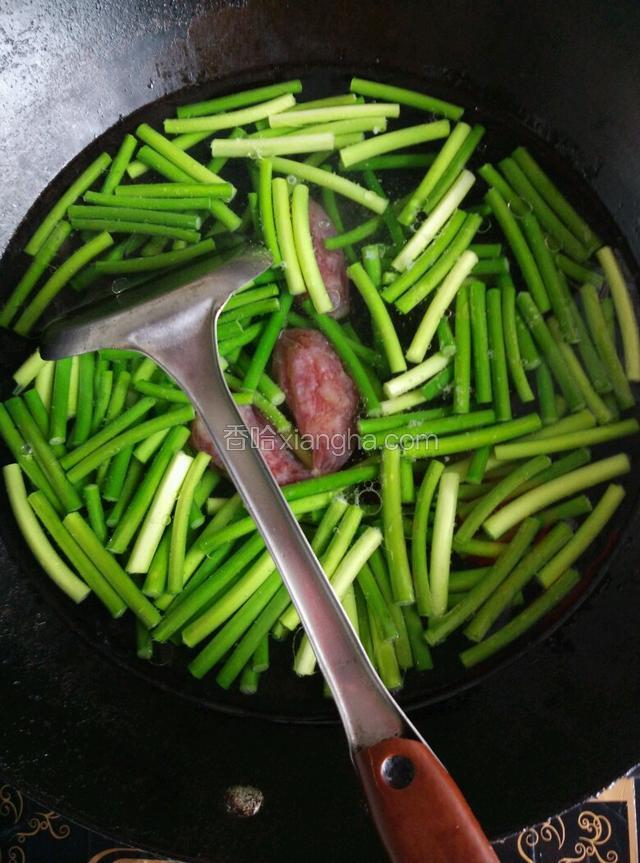 倒入准备好的腊肠及蒜心，加适量的盐调味，煮至蒜心断生