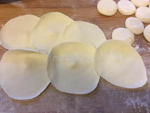 用擀面杖把剂子擀成中间厚边缘薄的饺子皮。
