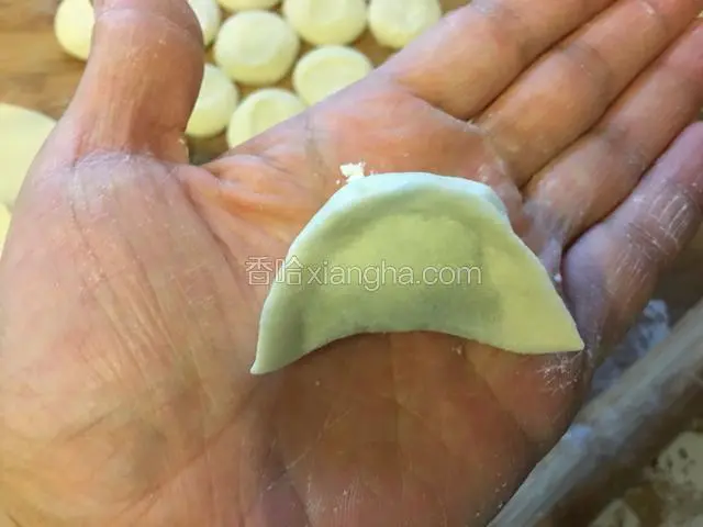 饺子皮上下对折，先捏紧中间，再捏紧两边，一个饺子生坯就捏好了。