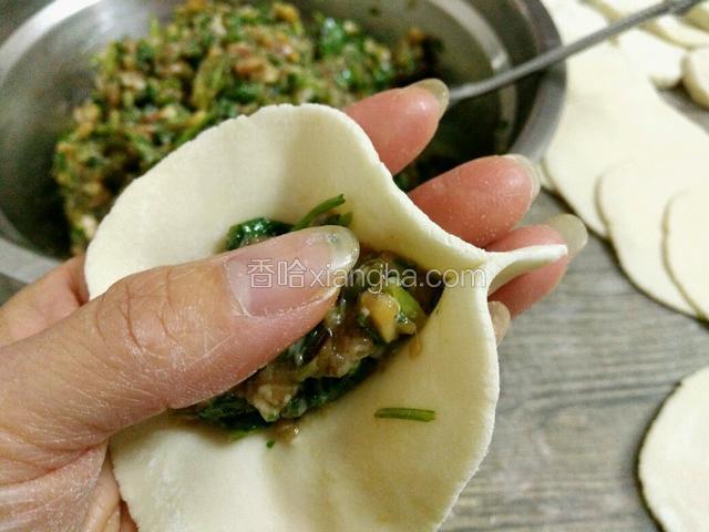 饺皮右边对折，用右手大拇指和食指捏紧