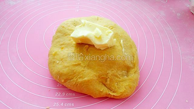  揉成光滑的面团后移至案板上，加入软化的黄油继续揉搓面团，一开始会比较粘手，需要一些耐心。