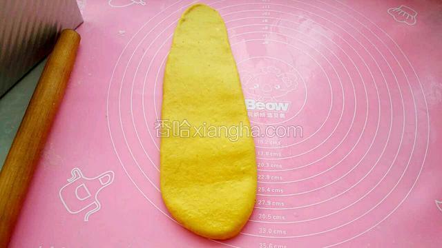 取一个松弛好的面团揉匀后擀成长度约30厘米的长舌状。