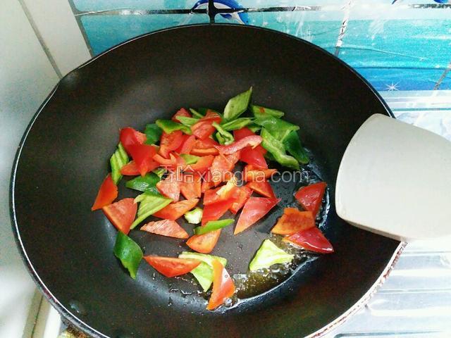 锅内倒入少量油，放一点点盐煸炒青红椒约八成熟。