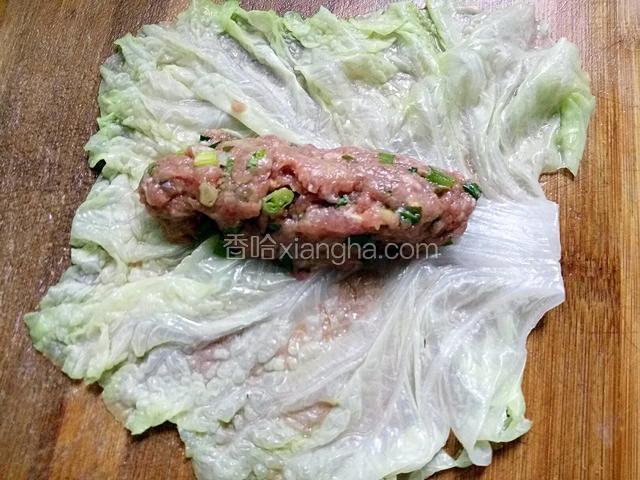 在把白菜叶拿出，上面放上拌好的肉