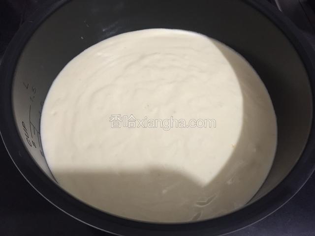 把电饭煲内胆从电饭煲里取出来，再把翻拌好的蛋糕糊倒入内胆里，用手端着内胆在桌子上震两下，把内部的气泡给震出来。