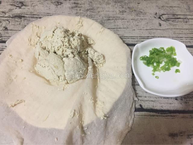 然后把豆腐放入纱布包上挤去水份，葱切葱花备用