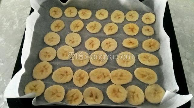 烤盘里铺油纸，放入香蕉片，再撒上白糖