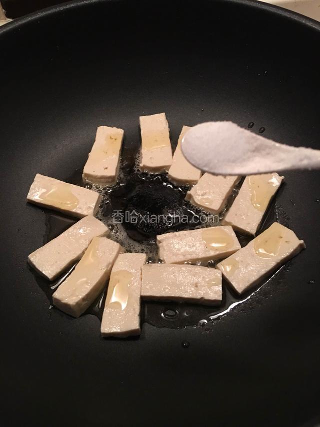 热油锅，豆腐切成均匀的薄片，放锅里煎，每一块豆腐撒上少许盐（另外一面不用放盐）