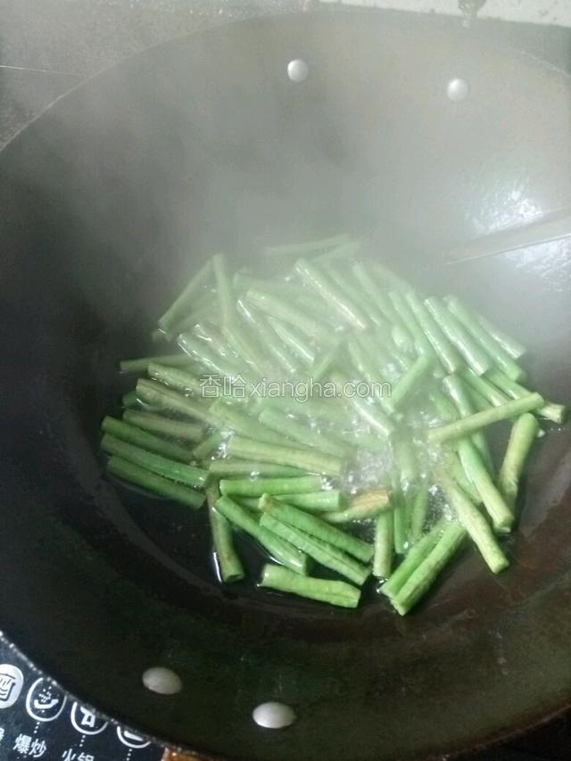 下比平时做菜多一倍的油，豆角沥干水，下锅煸炒