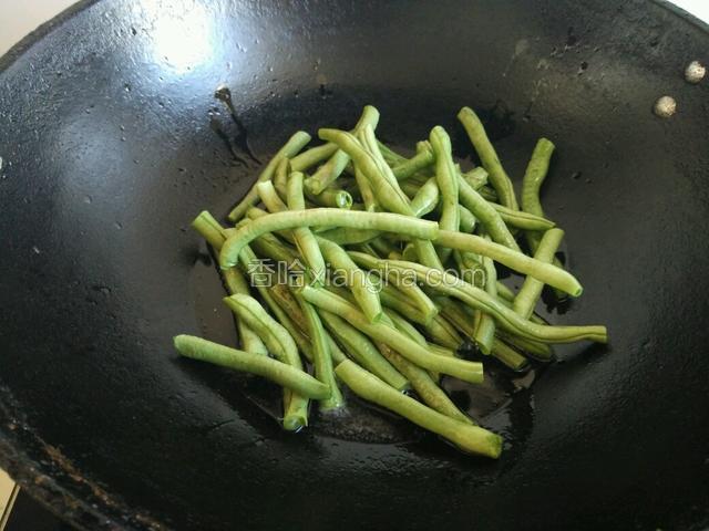 锅内放植物油，将豆角放入，用油煸炒