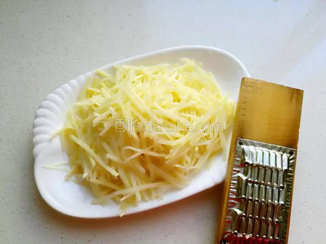 土豆用擦丝器擦成丝。
