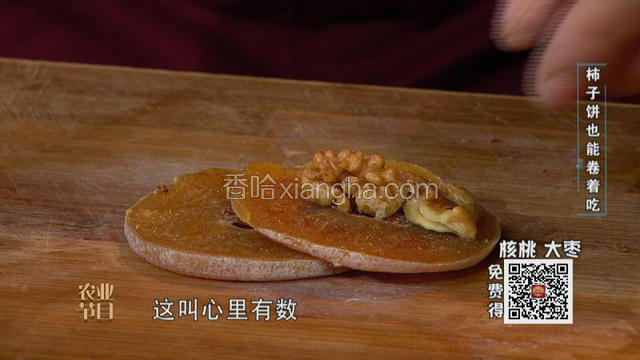 将柿饼敲松，切成两半，将炒好的核桃仁卷在其中切断。