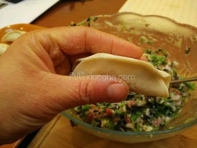 将饺子皮边缘捏紧，左右两边各留一小截距离。
