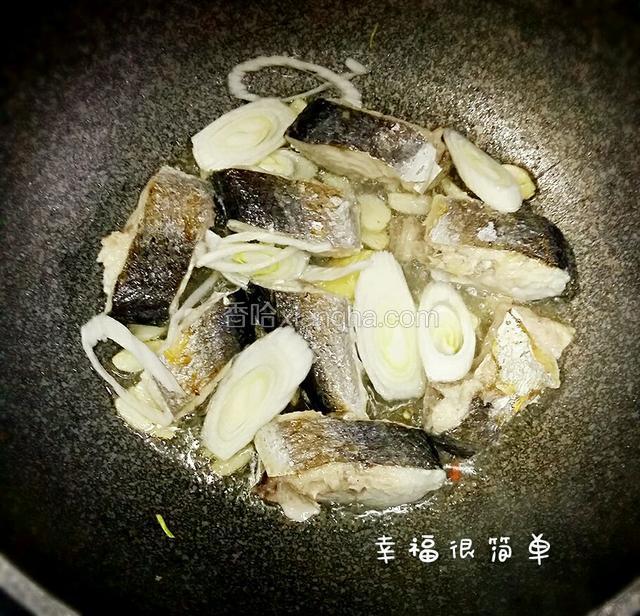 一面煎制完翻面，再放入蒜片和大葱白切片，烹入适量的料酒继续煎制。