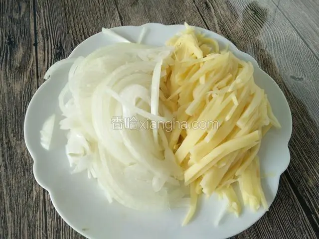 土豆用刀切成土豆丝。元葱也切成元葱丝，装在一个盘子里备用。