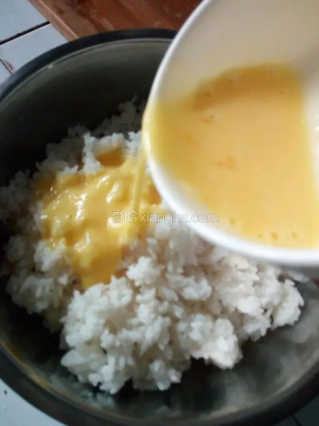把提前冷藏过夜的隔夜米饭搅成颗粒状，再倒入打散的鸡蛋液，拌匀。