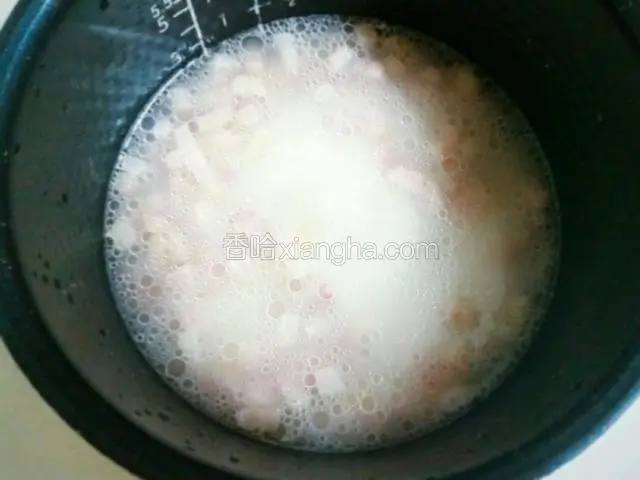 煸炒好的咸肉丁连同锅里的油一起倒入电饭煲里稍做搅拌。