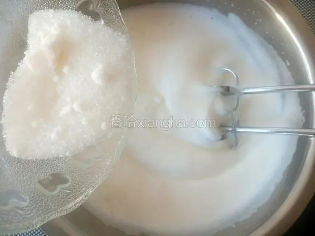继续用电动打蛋器中速搅打，打至蛋白体积膨大，稍有纹路时再加入1/3的细砂糖。