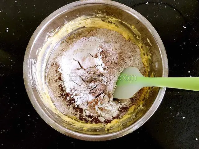 将混合粉筛入黄油蛋液中，用橡皮刀翻拌均匀至无干粉。