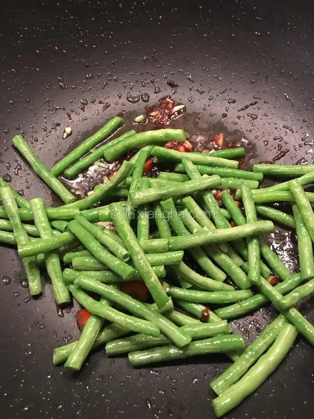 把备好的豆角入锅，放少许的盐翻炒均匀。