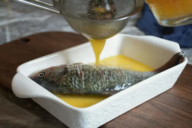 弃掉腌制的汤汁、葱姜，将鱼摆入汤盘，用滤网过滤蛋液，倒入汤盘，液面不要高于鱼身。