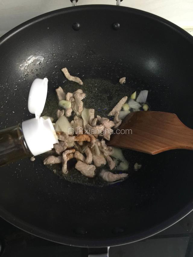 肉炒变色后加入葱，蒜片爆香，淋入少许生抽，料酒翻炒。