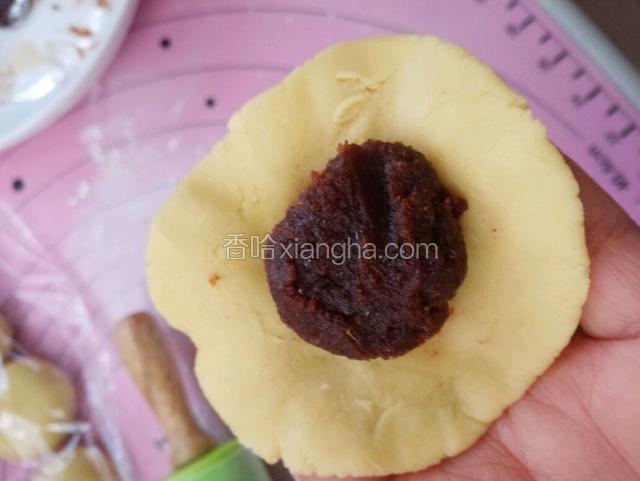 把面剂擀成圆片，把豆沙馅放到圆片中间