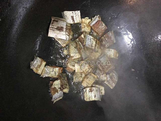 热油锅下带鱼干翻炒接着倒入适量的料酒