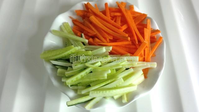 将胡萝卜和黄瓜分别切成均匀细丝，放入盘中。