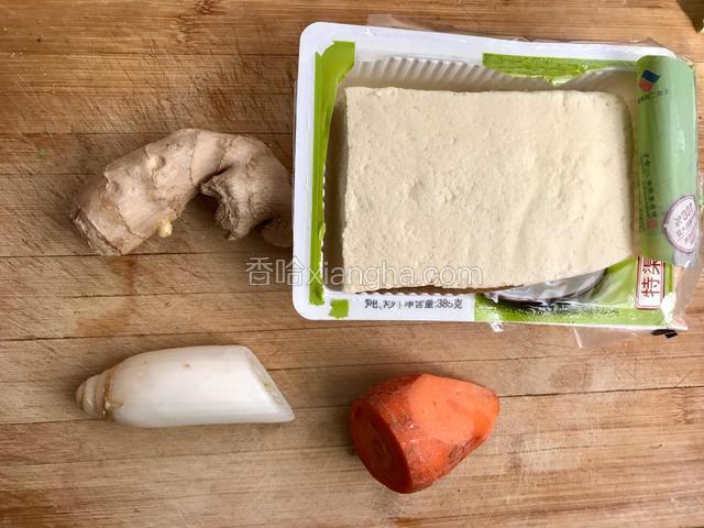 准备配料：豆腐用勺子按碎、胡萝卜刮成小丝、葱姜切末。