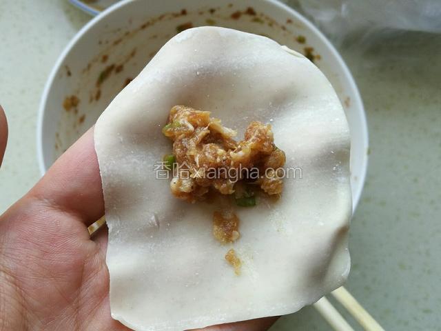 取一张馄饨皮，在正中间放入适量拌好的肉馅。