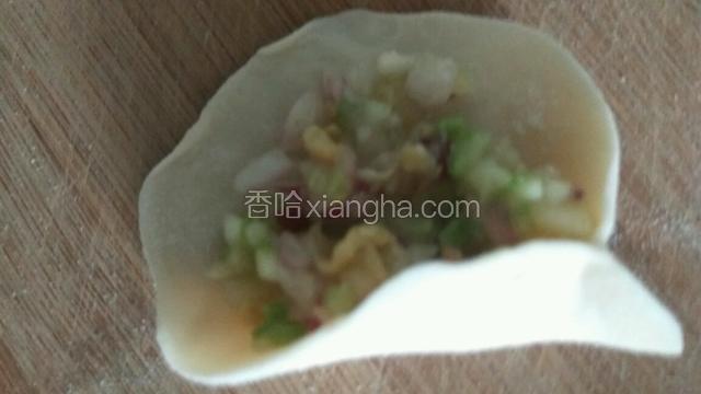 取一张饺子皮，拇指和食指从一端捏住。