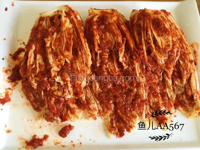 腌制好的白菜挤去水分，抹上辣椒糊，每个白菜叶都要抹上。