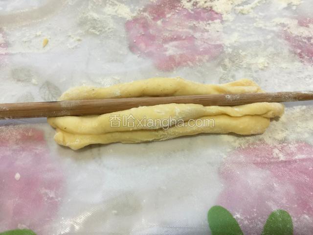 醒好的面团分成长条小剂子，两个面条叠一起，用筷子压一下，然后扭一下。