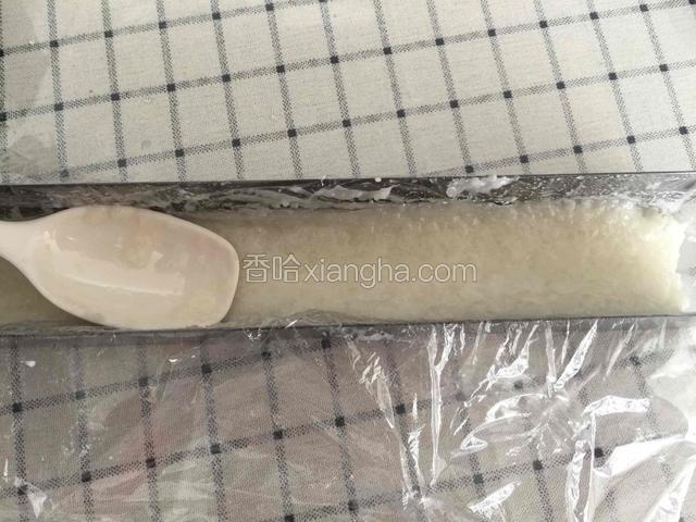 取少许糯米放入铺好保鲜膜的模具里压实。不好操作就在工具上沾点凉开水，这样糯米酒听话了。