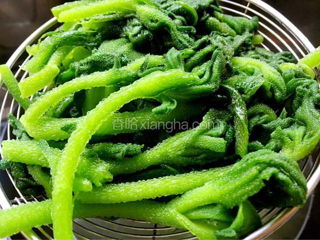捞出用纯净水冲凉，保持它的绿色，挤干水份放入盘中。