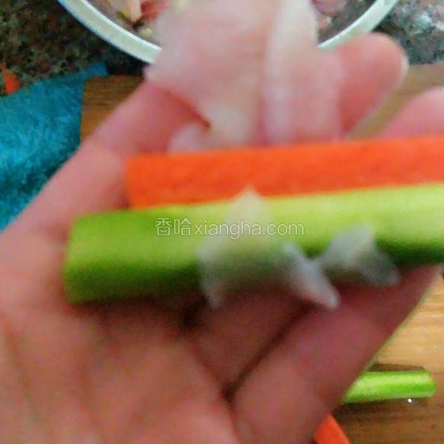 取一张鱼片摊开，放上胡萝卜芦笋各一节，再卷起，尾部粘上一点干淀粉，就能粘住了
