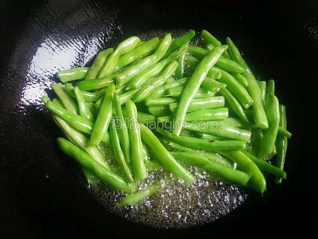 下四季豆煸炸，炸成皮成虎皮样，再将油全部倒出锅不用。