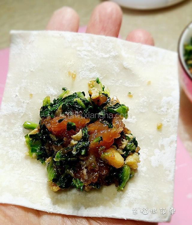 取一张馄饨皮，一端放入适量的菜肉馅。