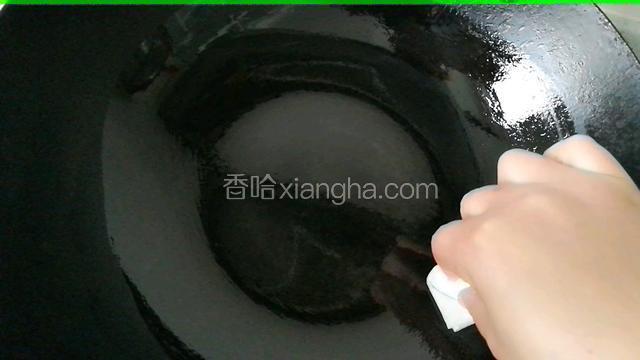 取一干净无水小碗，倒入适量食用油。用厨房纸蘸取适量食用油在锅底均匀的涂抹一层。