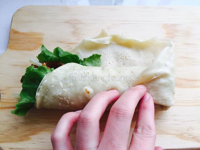 由下向上包住菜卷起，剩三分之一饼皮时把尾部的饼皮折起来后再卷向上卷起直到卷完。