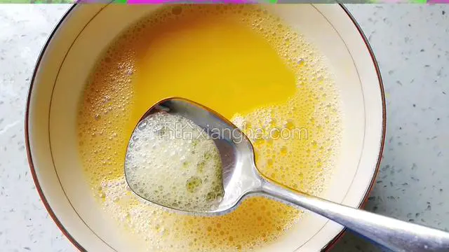 用勺子撇去蛋液表面的浮沫。