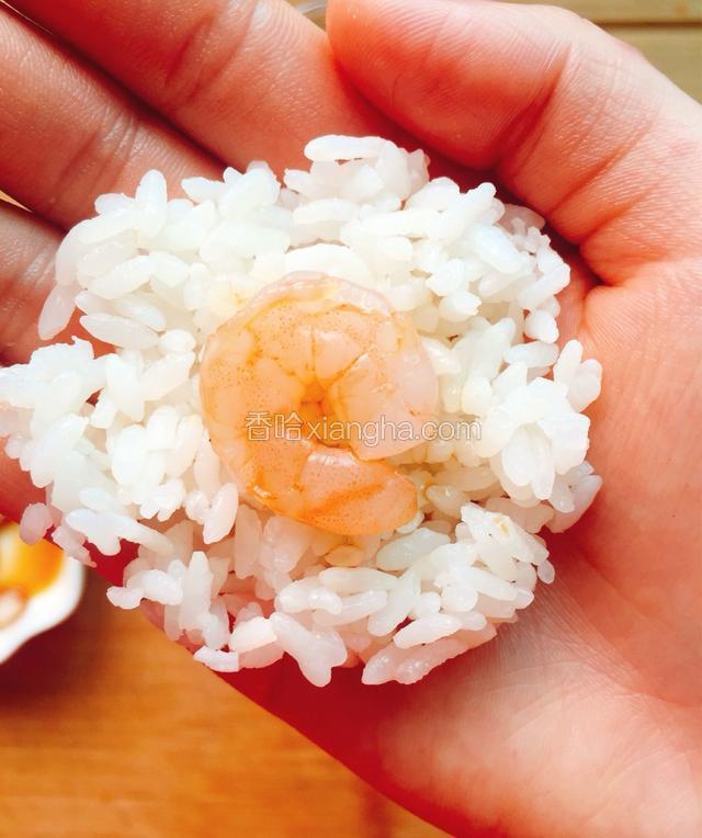 放入一颗虾仁，将虾仁两边的米饭包裹住虾仁。