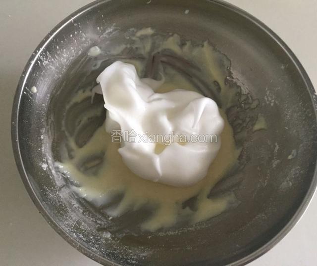 取三分之一的蛋白霜加入到奶粉糊中上下翻拌均匀