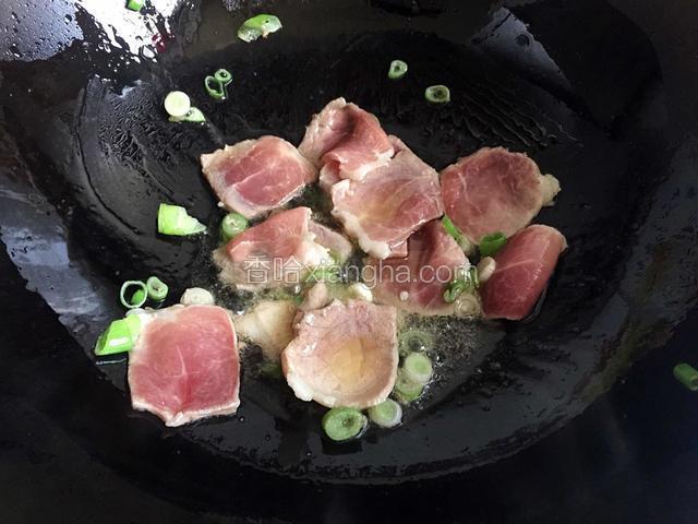 锅内放油烧热，放入葱末和肉片翻炒至肉片变色。