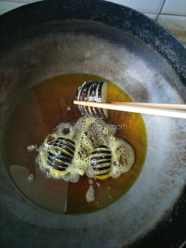 锅中倒多点的油烧热，把茄子一个一个的放入油锅中小火炸（我这是菜籽油）