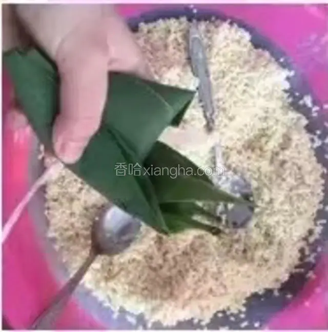 把糯米抖抖，结实点，
下面这一步比较难——
左手握住粽体，右手拿粽叶，再左手往右手扣，右手的粽叶盖住糯米，左手把两边的糯米向前捏，把两边的粽叶保住粽体，右手把剩余的粽叶往边上按，往粽子上捆竹条就行（捆绑的方法有很多种）