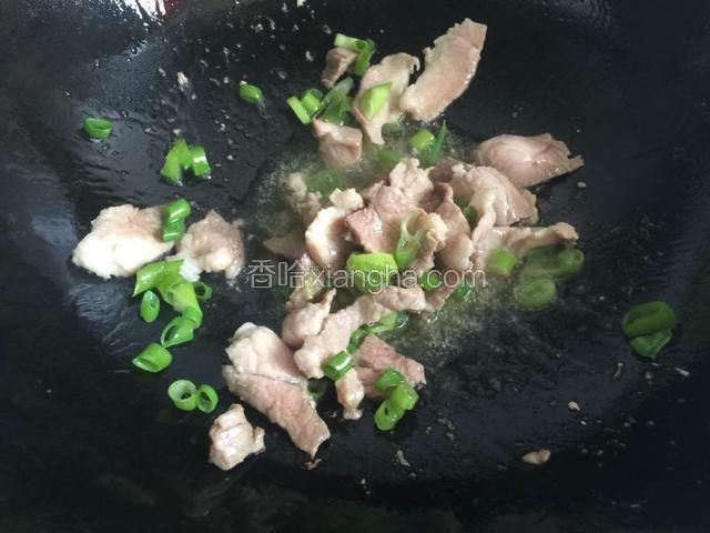 待肉片变色后放入葱末翻炒。