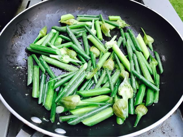 再将剩余的一茶题油烧热炒蒜苔。翻炒蒜苔放水和调酒和少许生炒。盖上锅盖烧五分钟，蒜苔八成熟就可以。