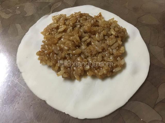 在饺子皮上先放一层糯米饭；